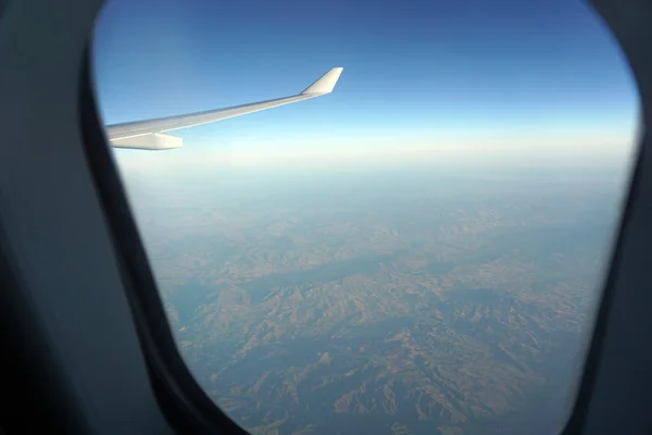 Beautiful view from the window of the aircraft. Concept and copyspase for travel, holidays and vacation. Sea, mountains, clouds, coastline, horizon, blue sky through the eyes of a traveler.