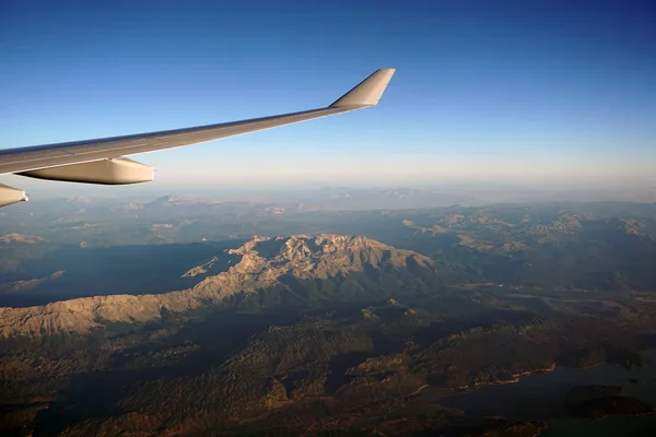 Beautiful view from the window of the aircraft. Concept and copyspase for travel, holidays and vacation. Sea, mountains, clouds, coastline, horizon, blue sky through the eyes of a traveler.