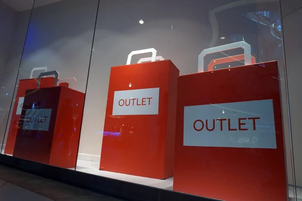 Red sign Outlet on a shop window. Sale in a clothing store