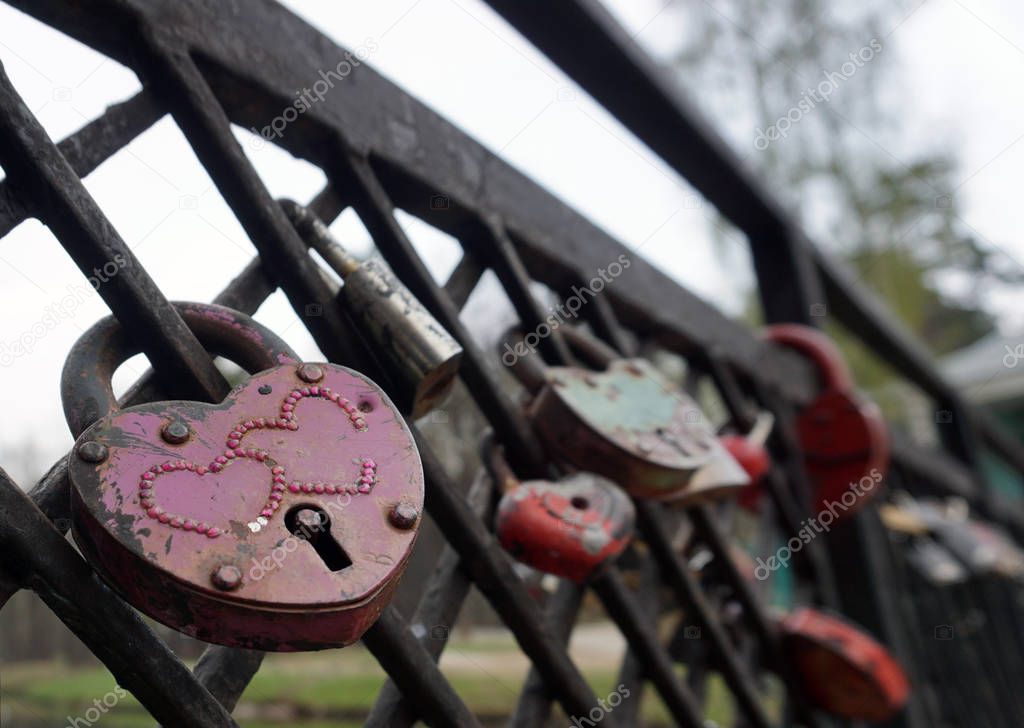 Symbolic love padlocks red color shape heart fixed to the railings bridge as a eternal love sign.