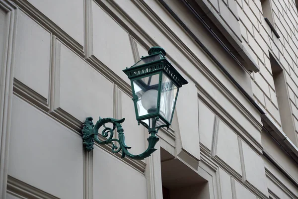 A vintage street lamp attached to the wall of a historic building.