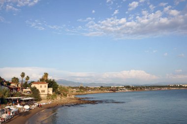 Side / Turkey - 16 Ekim 2019: Deniz kıyılarının, plajların, evlerin muhteşem manzarası. Mavi bir gökyüzünde parçalı bulutlu ve ufukta dağlar. Türkiye 'de harika bir tatil.