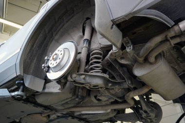 Tamir için kaldırılan modern lüks bir araba. Fotoğraf aşağıdaki arabanın yapısını ve elementlerini gösteriyor: arka süspansiyonun tasarımı, yaylar, egzoz sisteminin parçaları..                               