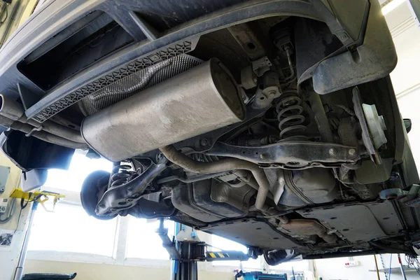 修理のためにリフトで調達されたサービスの現代的な高級車 写真は 以下の車の構造と要素を示しています リアサスペンション スプリング 排気システムの一部の設計 — ストック写真