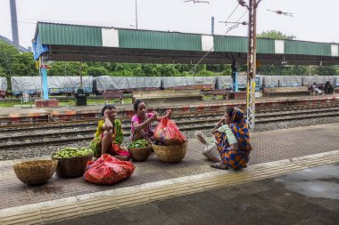 Bir tren istasyonu platformunda sebze satan bazı mutsuz yoksul Hintli kadınların Samimi fotoğraf