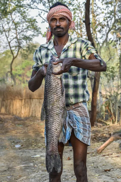 黑皮肤的印度渔夫手里拿着一条草鲤鱼（克特诺芬戈顿·伊德拉）鱼 — 图库照片