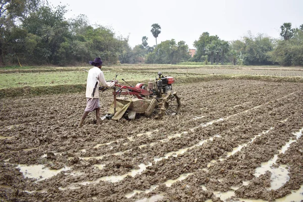 Человек, обрабатывающий землю руками, рисовым полем, ручным трактором — стоковое фото