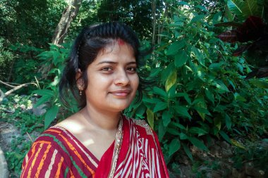 Güzel bir Hintli ev kadınının portresi. Geleneksel giysiler içinde. Ormanda makyajsız.