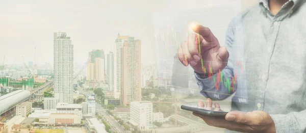 Businessman working outdoor checking stock market view on the hologram screen from the smartphone, double exposure concept.