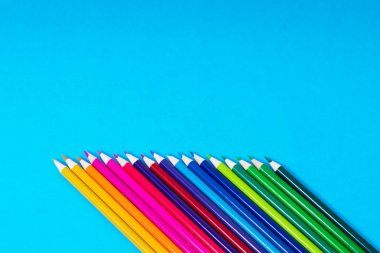 Mavi arka plan üzerinde bir açıyla renkli kalemler