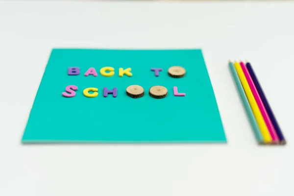 Turquoise notepad with text Back To School laid on it. Colored pencils by the side. Isolated. — Stock Photo, Image