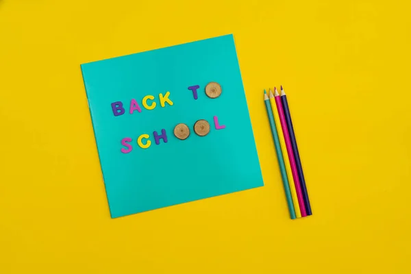 Texte de retour à l'école sur un bloc-notes avec crayons de couleur à côté sur fond jaune orangé . — Photo
