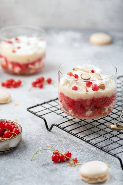 Kırmızı frenk üzümü, muhallebi, badem çekirdekleri ve gri arka planda cam krema ile hafife