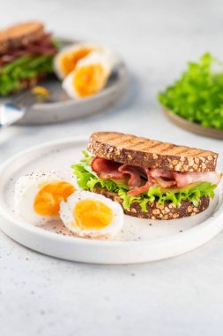  Pastırmalı sandviç, siyah ekmek, tabak üzerinde salata