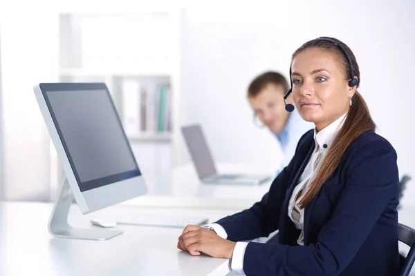 Ευτυχισμένη γυναίκα, φορώντας ακουστικά και να κάθεται στο γραφείο του. επιχειρηματίας . — Φωτογραφία Αρχείου