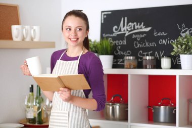 Tarifi arıyorum genç kadın mutfakta yemek kitabı okuma. Genç kadın