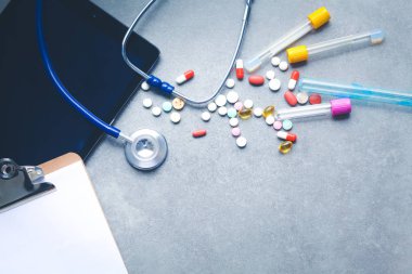 Tıbbi ekipman: mavi stetoskop ve tablet gri arka plan üzerinde.