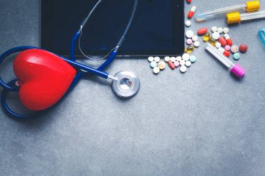 Tıbbi ekipman: mavi stetoskop ve tablet gri arka plan üzerinde.