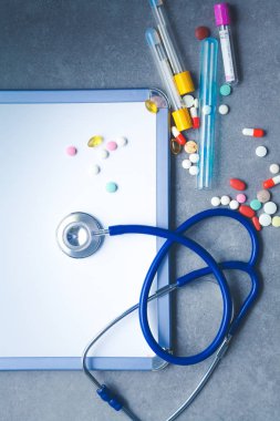 Tıbbi ekipman: mavi stetoskop ve tablet gri arka plan üzerinde.