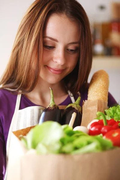 Молодая женщина держит сумку с овощами, стоящими на кухне. — стоковое фото