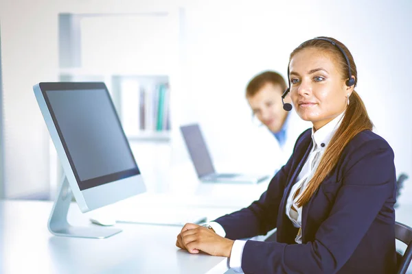 Gelukkig vrouwelijk dragen van hoofdtelefoon en zitten op het Bureau. zakenvrouw . — Stockfoto