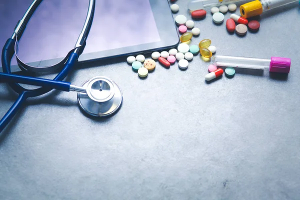 Medische apparatuur: blauwe stethoscoop en tablet op grijze achtergrond. — Stockfoto