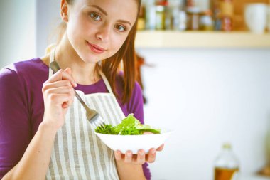 Genç kadın taze salata modern mutfakta yemek. Mutfak at genç kadın