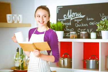 Tarifi arıyorum genç kadın mutfakta yemek kitabı okuma. Genç kadın