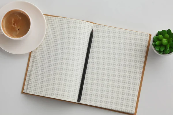 Bovenaanzicht beeld van notitieblok openen met lege pagina's naast een kopje koffie op houten tafel. — Stockfoto