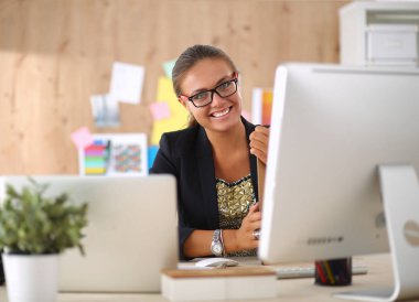 Moda tasarımcıları stüdyoda çalışıyor. Masanın üzerinde oturuyorlar.