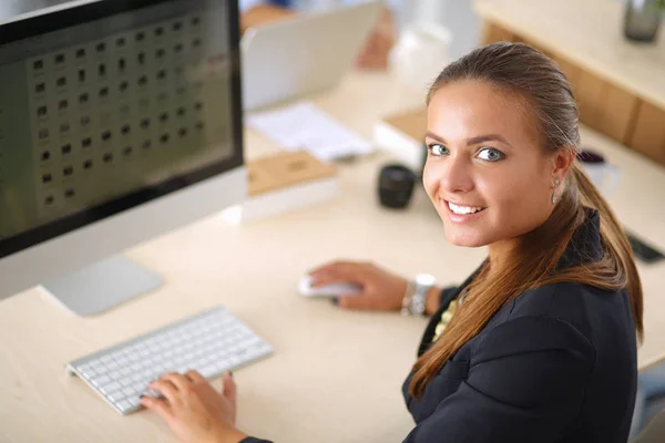 Młoda kobieta pracuje w biurze, siedząc przy biurku, za pomocą laptopa — Zdjęcie stockowe