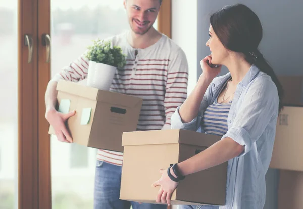 Feliz jovem casal desembalagem ou embalagem caixas e se mudar para uma nova casa — Fotografia de Stock