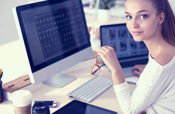 Ofiste çalışan genç bir kadın, masada oturuyor.