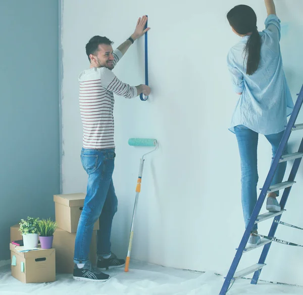 Portret van gelukkig lachend jong koppel schilderij interieur wand nieuw huis — Stockfoto