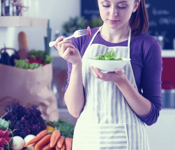 Junge Frau isst frischen Salat in moderner Küche — Stockfoto