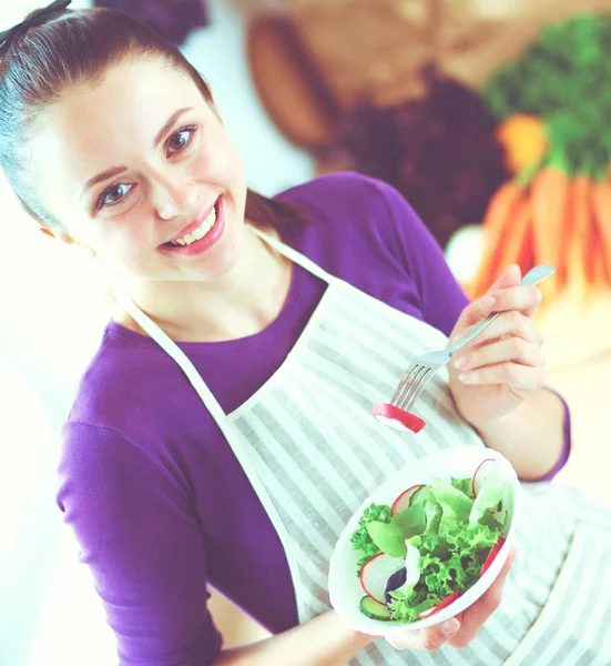 Nuori nainen syö tuoretta salaattia modernissa keittiössä — kuvapankkivalokuva