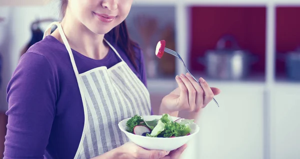 Jonge vrouw die verse salade eet in de moderne keuken — Stockfoto