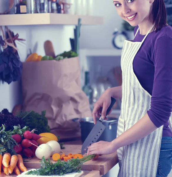 Junge Frau schneidet Gemüse in der Küche — Stockfoto