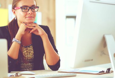 Moda tasarımcıları stüdyoda çalışıyor. Masanın üzerinde oturuyorlar.