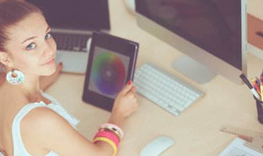 Ofiste çalışan genç bir kadın, masada oturuyor.