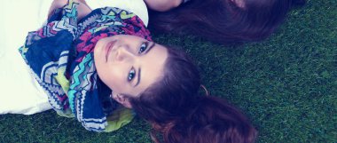 Taze yeşil çimlerin üzerinde yatan iki güzel kız 