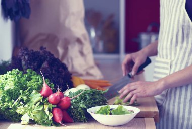 Mutfakta sebze doğrayan genç bir kadın.