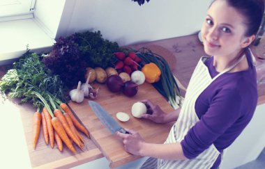 Mutfakta sebze doğrayan genç bir kadın.