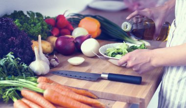 Mutfakta sebze doğrayan genç bir kadın.