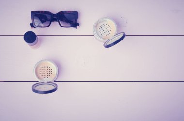 Güneş gözlüğü, kozmetik makyaj ve temel ahşap arka plan üzerinde