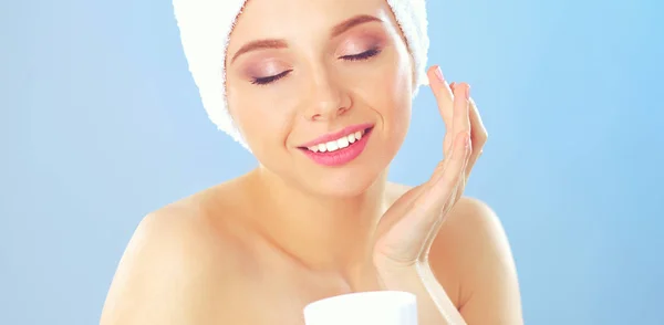 Mooie jonge vrouw, een crème op haar gezicht geïsoleerd op grijze achtergrond toe te passen — Stockfoto