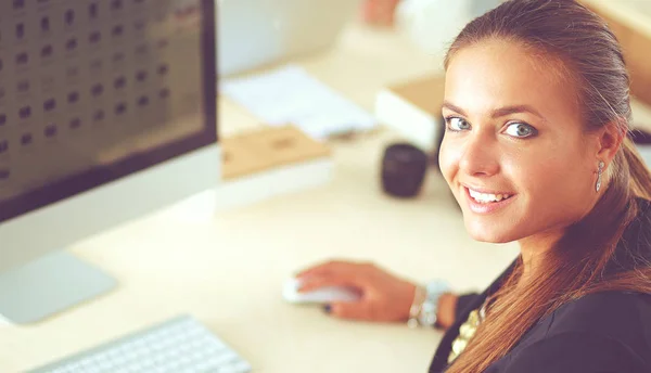 Dizüstü bilgisayar kullanarak masada oturan ofiste çalışan genç kadın — Stok fotoğraf