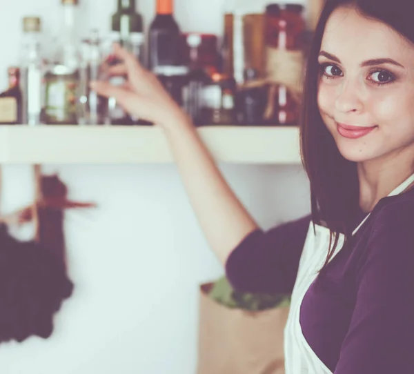 Mujer joven de pie en su cocina cerca del escritorio —  Fotos de Stock