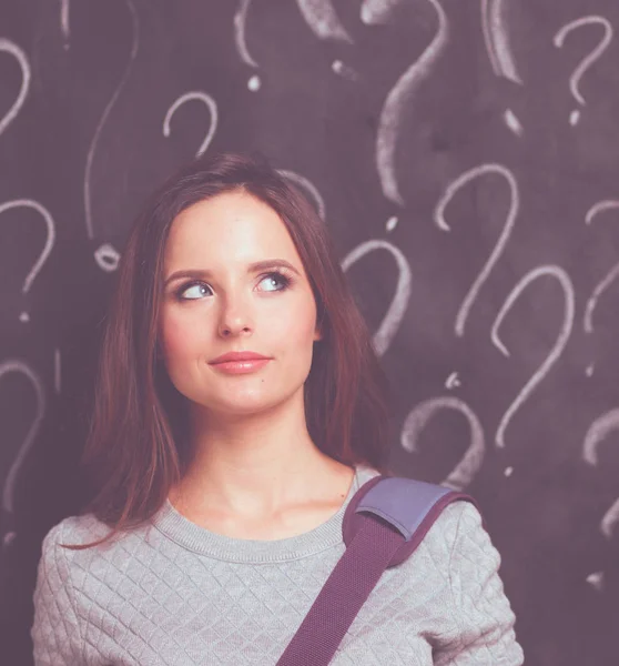 Young girl with question mark on a gray background — Stock Photo, Image
