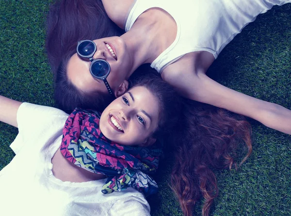 Taze yeşil çimlerin üzerinde yatan iki güzel kız 